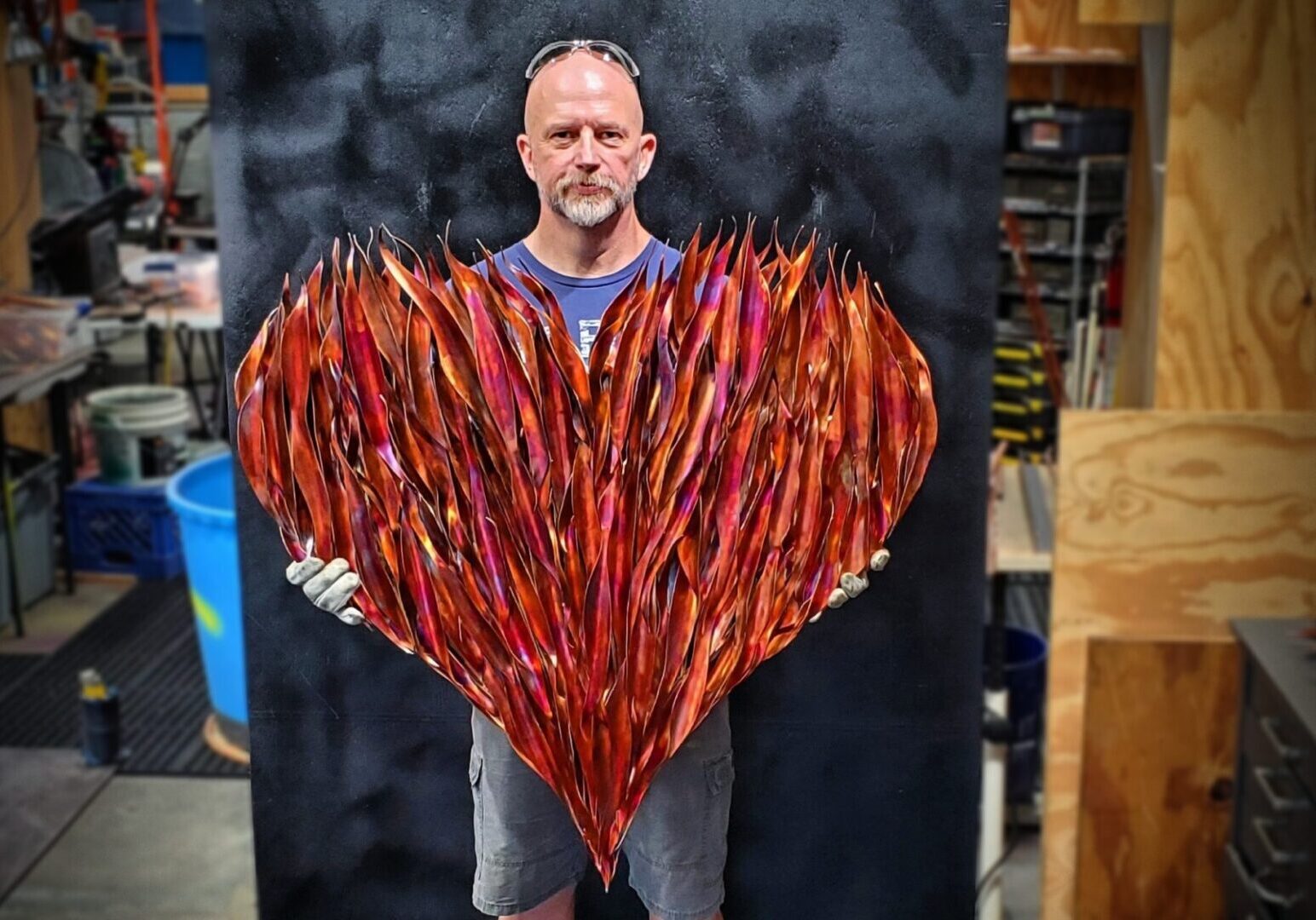 A man holding up a heart made of red sticks.